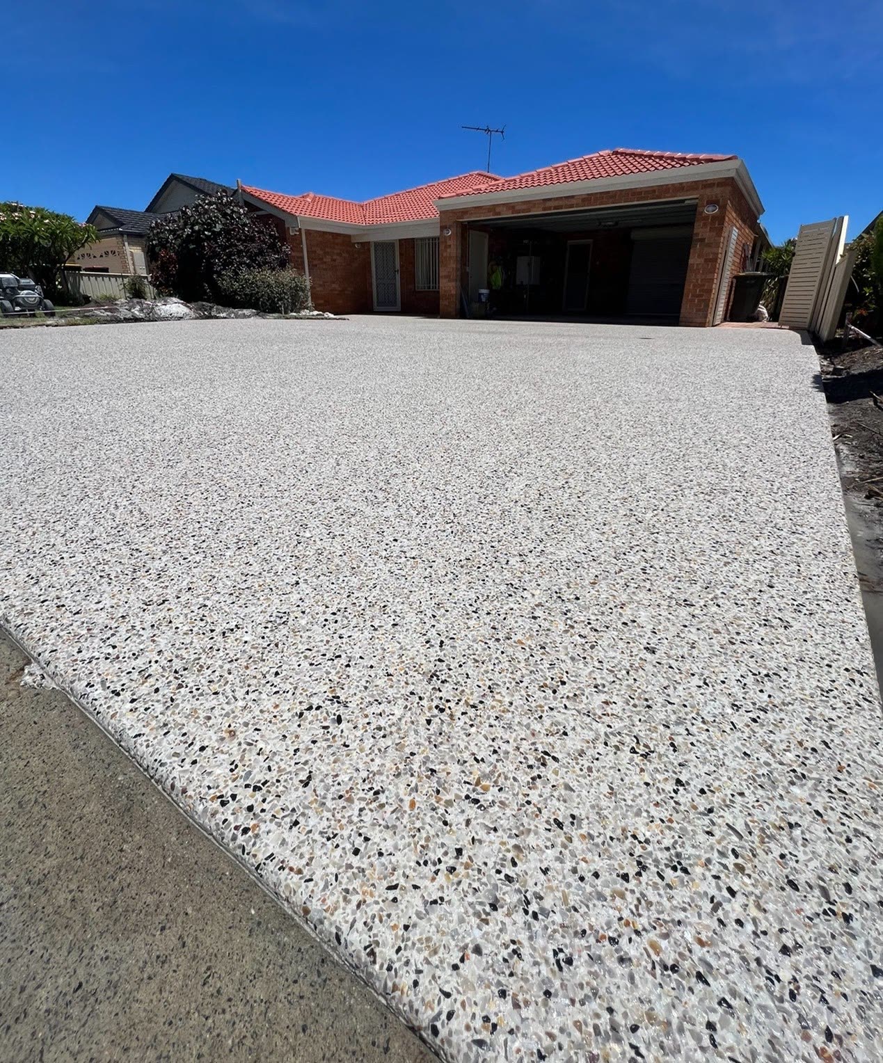 Exposed aggregate concrete driveway leading to a double garage